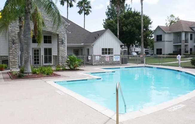 A swimming pool surrounded by palm trees and a white house.