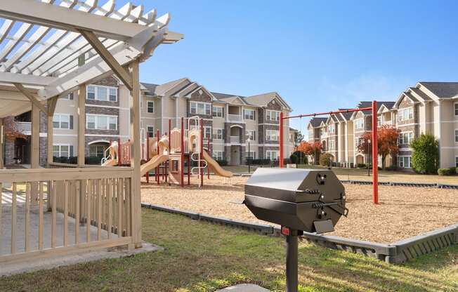 A playground with a slide and a swing set in front of apartment buildings.