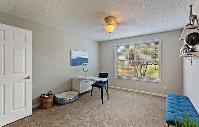 A room with a desk, chair, and window with blinds.