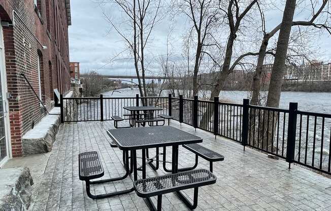 a patio with a table and benches next to a body of water