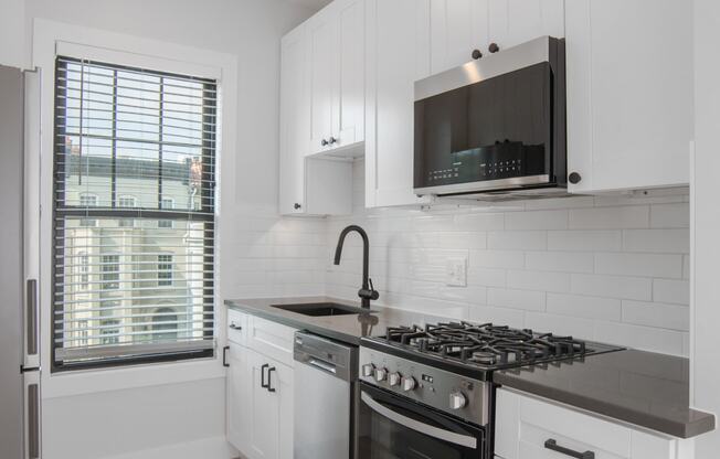 a kitchen with white cabinets and a stove and a window