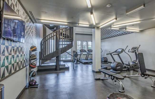 Two-story 24/7 fitness center featuring Technogym® cardio equipment with iPod connectivity, viewing screens for internet