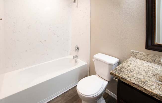A white toilet sits next to a bathtub in a bathroom.