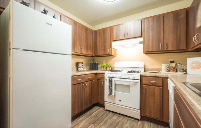 A white refrigerator is in a kitchen with wooden cabinets at Sterling Point Apartment Homes, Phoenix, Arizona