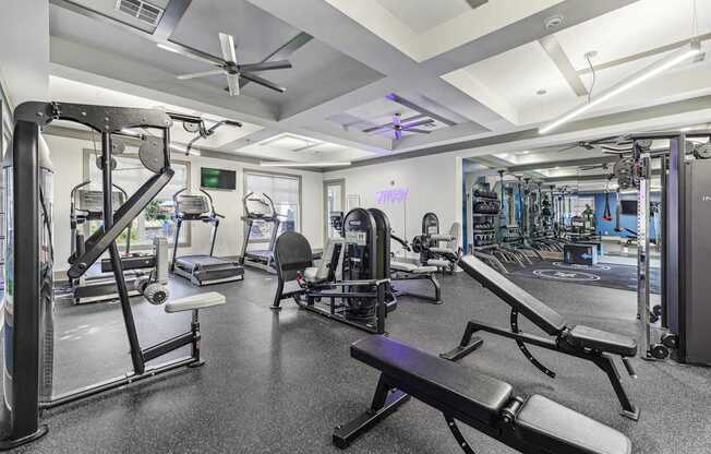 A gym with a variety of equipment including a bench, weights, and a fan.