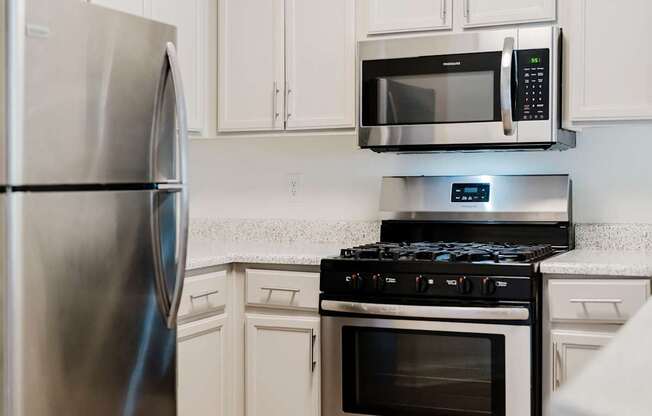 A modern kitchen with a stainless steel refrigerator, microwave, and stove.