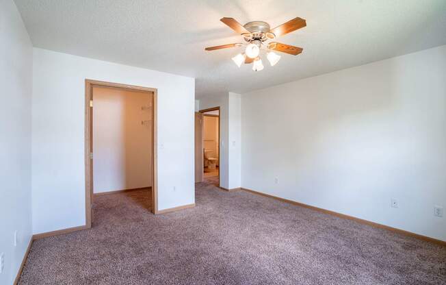 A room with a ceiling fan and carpeted floor. Fargo, ND Stonebridge Apartments