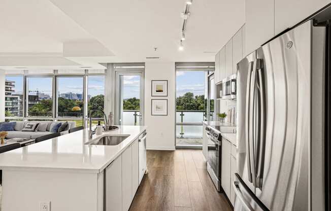 a white kitchen with a large island and stainless steel appliances