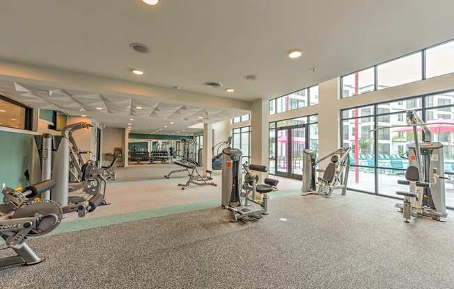 a gym with weights and other exercise equipment in a building with windows at Pinnacle Apartments, Jacksonville