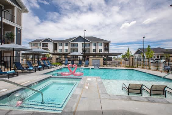 A swimming pool with a slide and chairs around it. at Connect at First Creek Apartments, Denver, CO