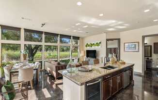 A modern kitchen with a large island and a dining table with chairs.