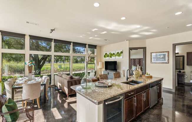 A modern kitchen with a large island and a dining table with chairs.