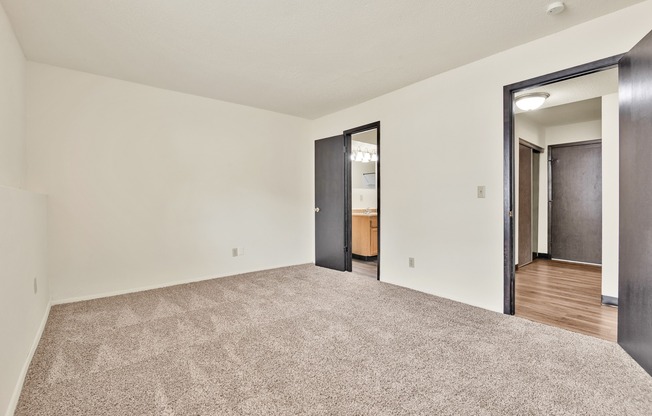 A room with a carpeted floor and two doors.