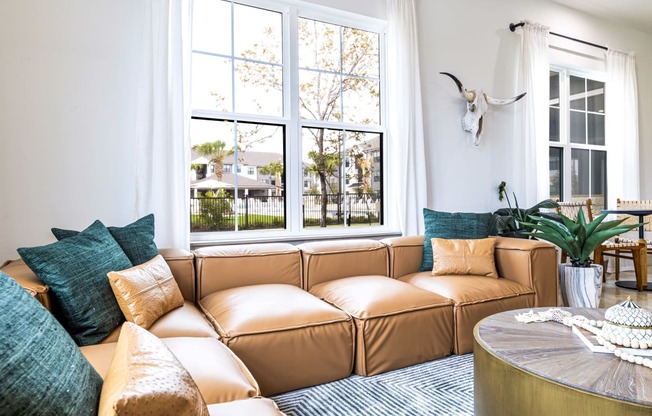 Living room with a brown couch and a large window at The Parker Austin, Pflugerville, Texas