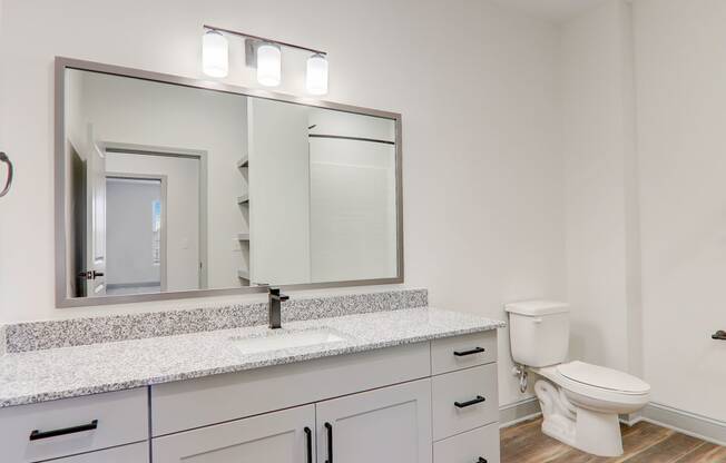 a white bathroom with a large mirror and a toilet