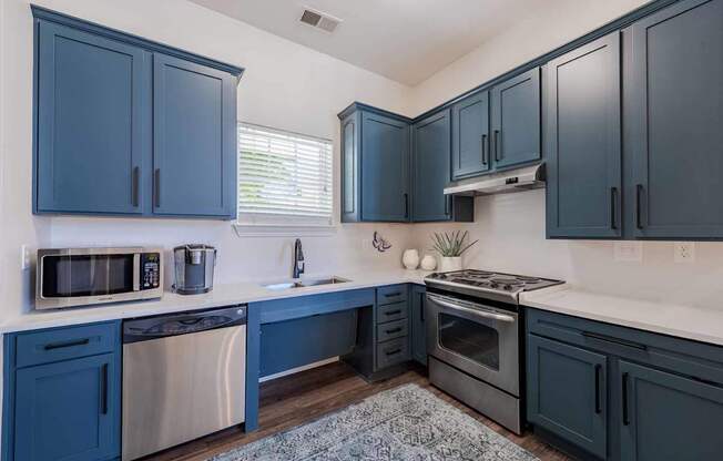 A kitchen with dark blue cabinets and stainless steel appliances.