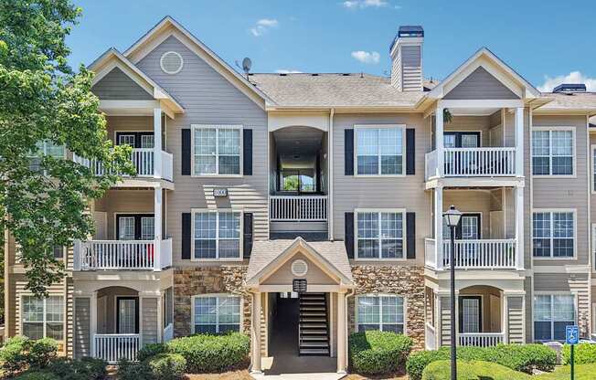 A large two-story apartment building with a stone facade and multiple balconies.