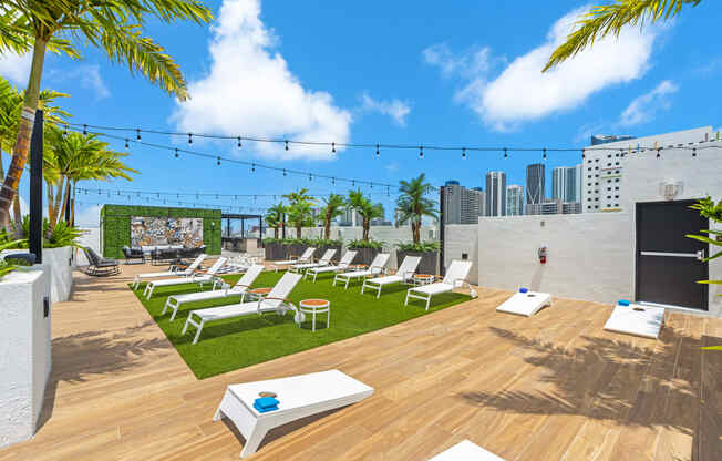 a roof top lounge area with lounge chairs and a view of the city