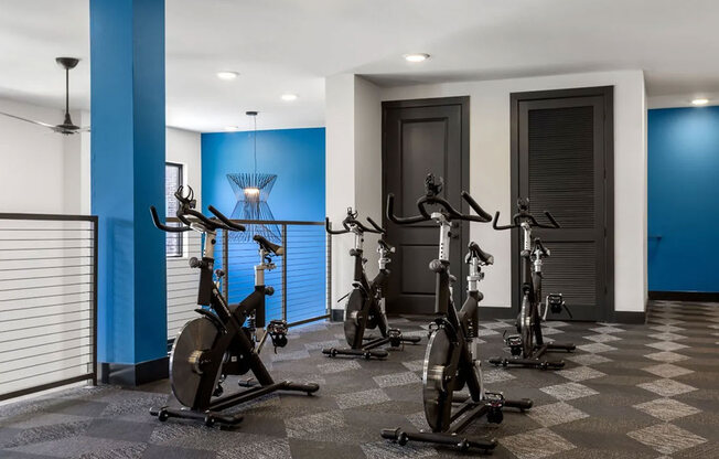 A row of stationary bikes are lined up in a room.