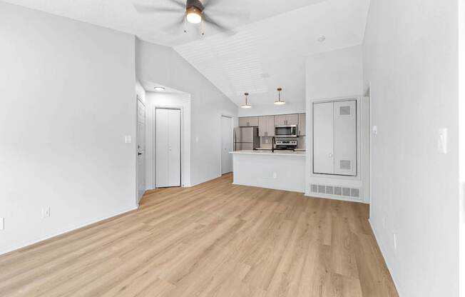 A room with a ceiling fan and a kitchenette.