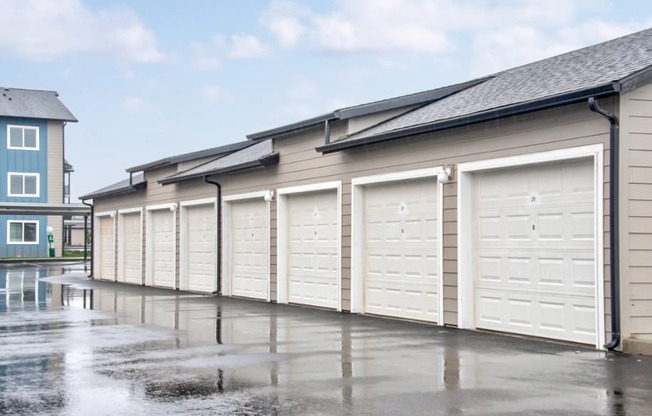 a row of garages with white doors in a parking lot