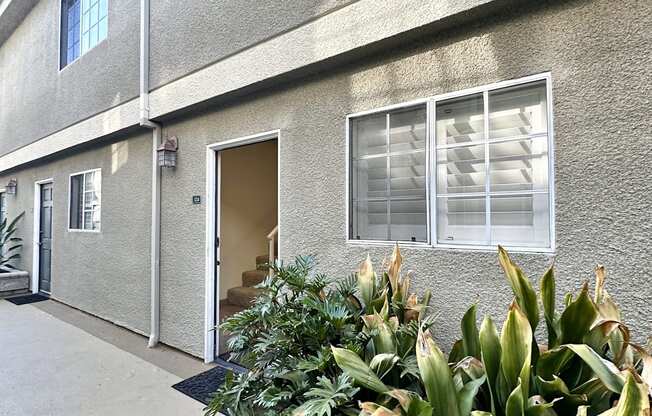 the front of a building with plants in front of it