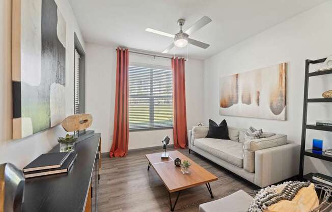 A living room with a couch, a coffee table, and a painting on the wall.