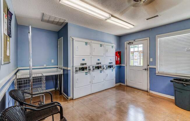 a room with blue walls and white cabinets and a table and chairs