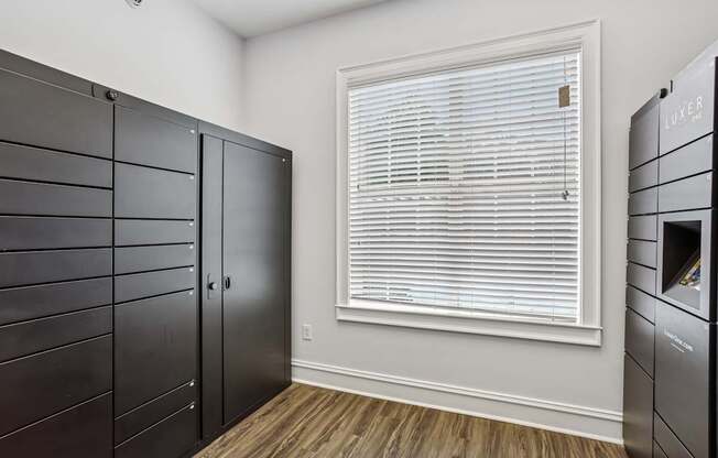 A room with a window covered by white blinds and a wooden floor.
