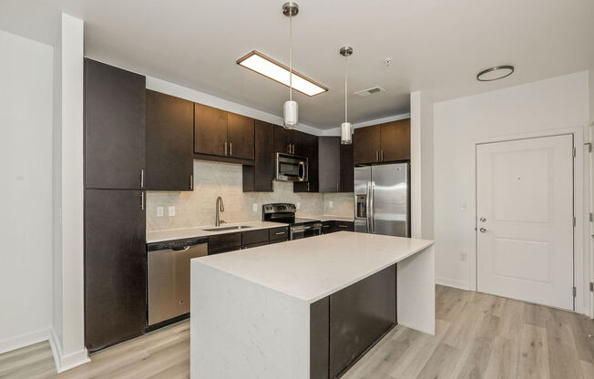 a kitchen with a large white island and stainless steel appliances