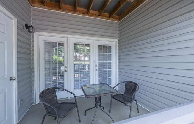 a covered porch with two chairs and a table