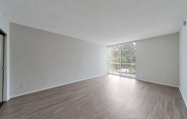 an empty living room with wood flooring and a window