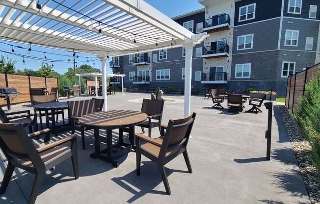 an outdoor patio with tables and chairs under a white canopy