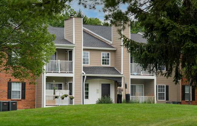 A large two story house with a balcony and a person standing in front of it.