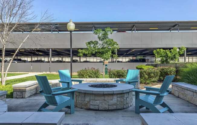 an outdoor patio with a firepit and blue adirondack chairs