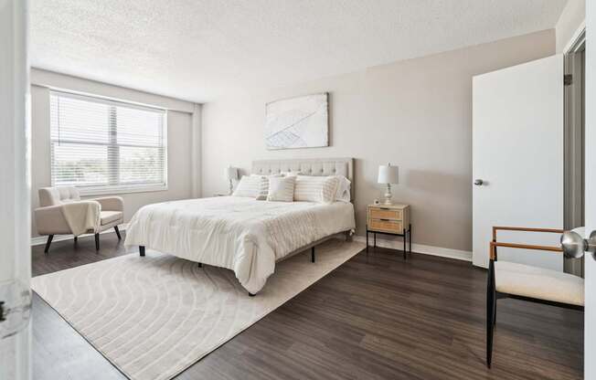 A bedroom with a large bed and a chair.