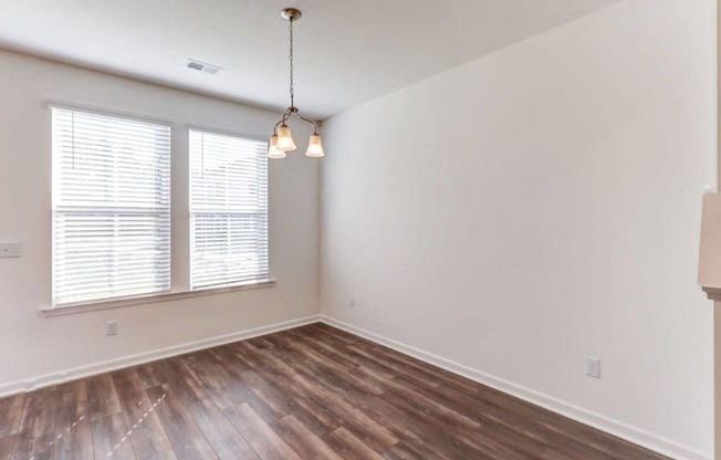 an empty living room with wood flooring and a window