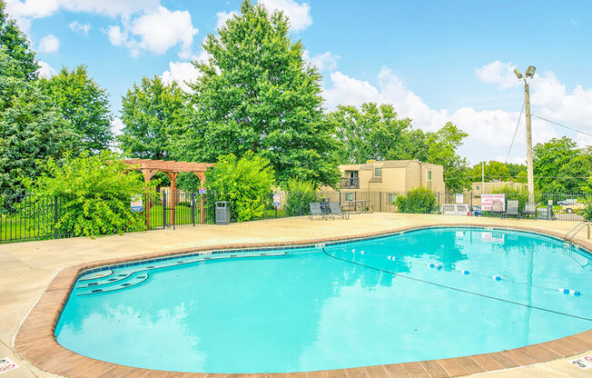 a swimming pool with trees and a building in the background