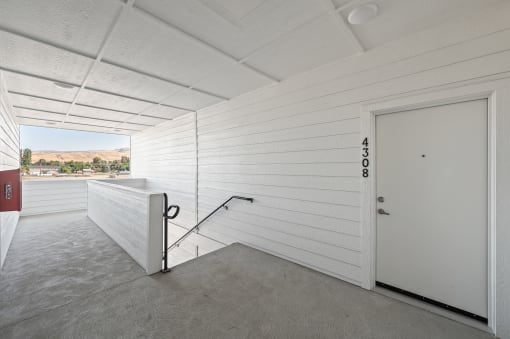 a room with a white wall and a door and a balcony at Gateway Apartments, East Wenatchee , Washington