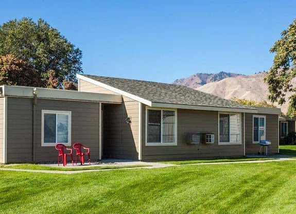 Exterior view of building with views of mountains in distance and grassy area.at Park View Apartments, Wenatchee, WA 98801