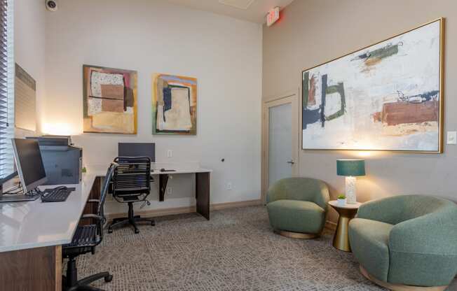 an office with a desk with a computer and chairs and paintings on the wall