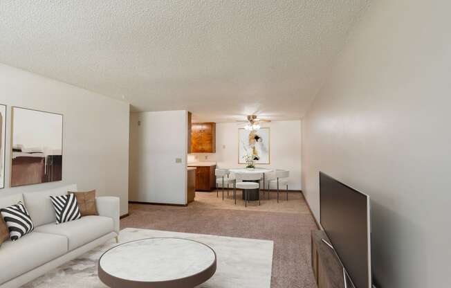 a living room with a couch and a coffee table and a dining room and kitchen. Fargo, ND Hawn Apartments