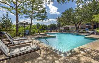 a resort style swimming pool with lounge chairs and trees at Lakeshore at Preston, Plano, TX