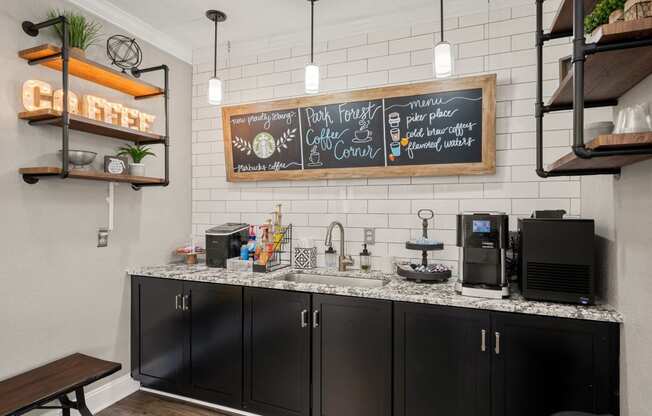 a kitchen with black cabinets and a counter top with a sink and a coffee bar