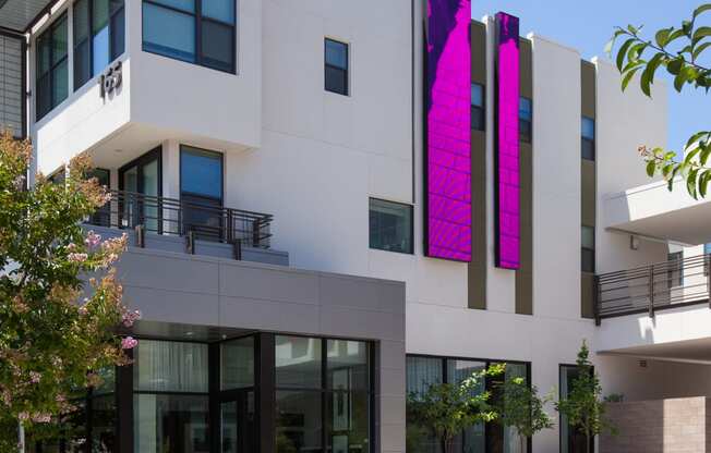 a white building with pink banners and trees