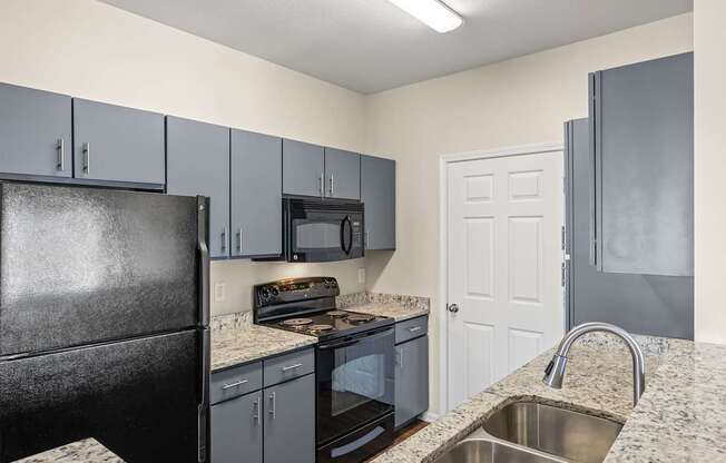 A kitchen with a black refrigerator and a white door.