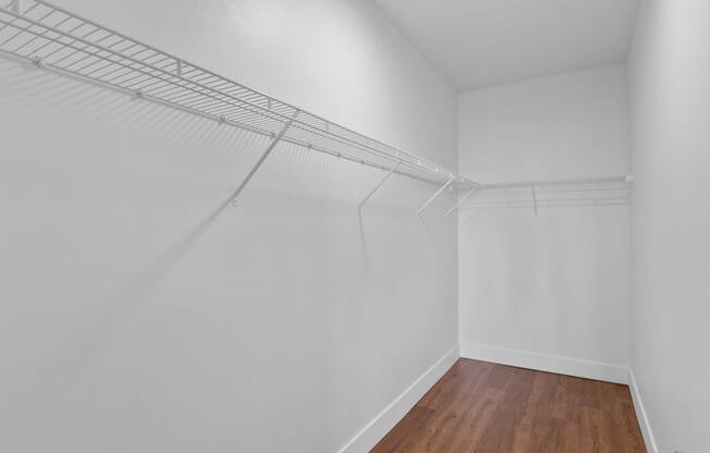 a bedroom with white walls and hardwood floors