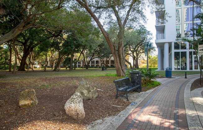 a park with trees and a bench in front of a building