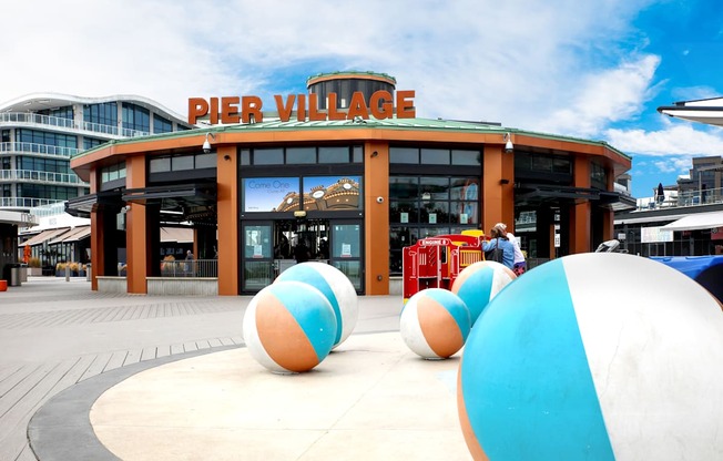 A large building with a sign that says "Pier Village" in front of it.
