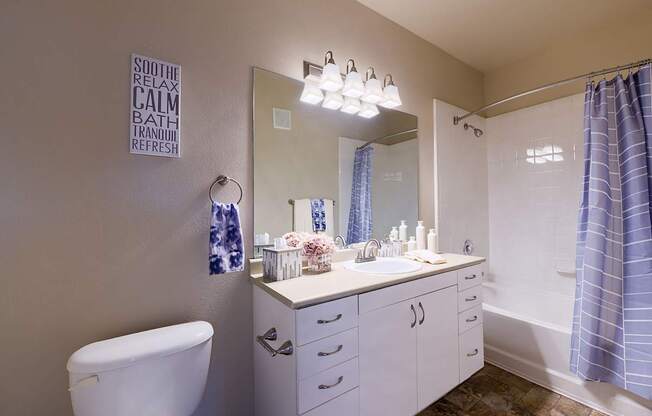 A bathroom with a white tub, sink, and toilet.